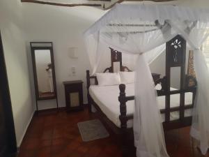 a bedroom with a bed with a canopy at MARIA, the Star on the sea beach cottages - cottage JIRANI in Malindi