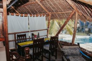 a dining room with a table and chairs and a pool at MARIA, the Star on the sea beach cottages - cottage JIRANI in Malindi