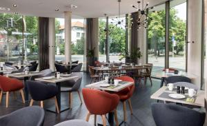 a restaurant with tables and chairs and windows at Vienna House Easy by Wyndham Osnabrück in Osnabrück