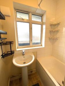 a bathroom with a sink and a tub and a window at Charming double-bedroom in London Flat in London