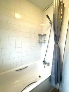 a bathroom with a bath tub with a shower curtain at Charming double-bedroom in London Flat in London