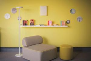 une chambre jaune avec une chaise et une lampe dans l'établissement Vienna House Easy by Wyndham Landsberg, à Landsberg am Lech