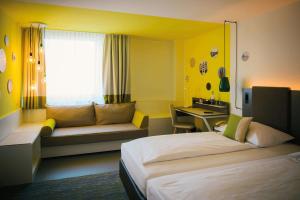 a hotel room with a bed and a desk at Vienna House Easy by Wyndham Limburg in Limburg an der Lahn