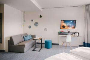ein Wohnzimmer mit einem Sofa und einem Tisch in der Unterkunft Vienna House Easy by Wyndham Coburg in Coburg