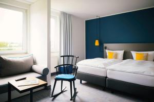 - une chambre avec un lit, une chaise et un canapé dans l'établissement Vienna House Easy by Wyndham Amberg, à Amberg