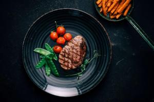 une assiette avec un steak et des légumes sur une table dans l'établissement Vienna House by Wyndham Andel's Cracow, à Cracovie