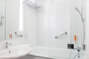 een witte badkamer met een wastafel en een douche bij Vienna House Easy by Wyndham Cracow in Krakau