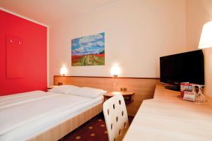 a bedroom with a large bed and a flat screen tv at Vienna House Easy by Wyndham Rostock in Rostock