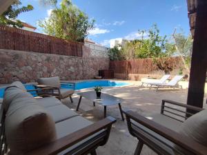 une terrasse avec un canapé et des chaises ainsi qu'une piscine dans l'établissement YalaRent Fruit Tree Villa with Private Pool, à Eilat