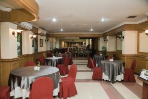 a restaurant with two tables and red chairs at Grand Inna Medan in Medan