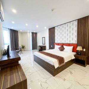 a bedroom with a bed and a desk and a television at Hoàng Triều Hotel - Marina Bình Dương in Thu Dau Mot