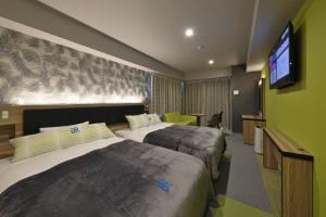 名護市にあるグリーンリッチホテル沖縄名護（人工温泉 二股湯の華）のベッド2台、薄型テレビが備わるホテルルームです。