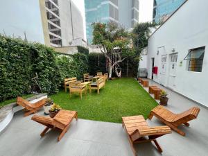 eine Terrasse mit Stühlen, Tischen und einem Rasenplatz in der Unterkunft Casaroma Hostels in Lima