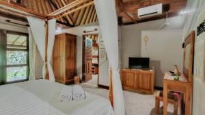 een slaapkamer met een bed met witte lakens en een televisie bij Dalai Tropical in Kuta Lombok