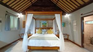 a bedroom with a canopy bed with yellow pillows at Dalai Tropical in Kuta Lombok