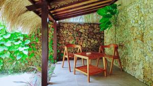 a table and chairs in a room with a stone wall at Dalai Tropical in Kuta Lombok