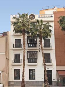 two palm trees in front of a building with a clock at THE CLOCK HOUSE Luxury Urban Suites in Málaga