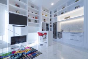a white kitchen with a flat screen tv and a red stool at THE CLOCK HOUSE - Luxury Urban Suites in Málaga +21 photos