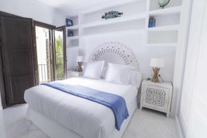 a white bedroom with a white bed and a window at THE CLOCK HOUSE Luxury Urban Suites in Málaga