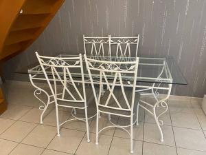 une table en verre avec deux chaises assises à côté d'un mur dans l'établissement Maison entière Chenôve avec jardin, à Chenôve