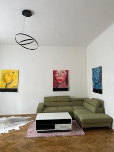 una sala de estar con un sofá verde y pinturas en ARTLIVING Apartment-Top 3 Self check-in en Graz