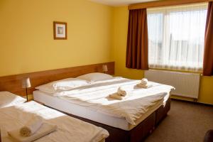 two beds in a hotel room with towels on them at Penzion Bojnice in Bojnice