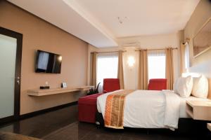 a hotel room with a bed and two red chairs at Grand Inna Medan in Medan