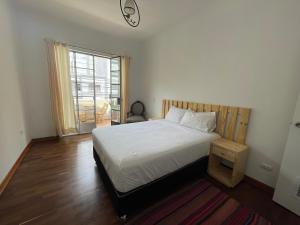 a bedroom with a white bed and a window at Casaroma Hostels in Lima