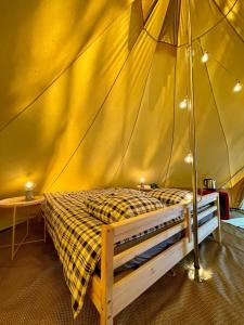 ein Schlafzimmer mit einem Bett in einem Zelt in der Unterkunft Tente Indiana Pins - La Téouleyre in Saint-Julien-en-Born