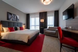 a hotel room with a bed and a chair and a desk at Hotel INCLUDiO in Regensburg