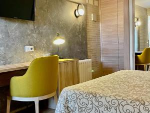 カネット・デ・ベレンゲルにあるHotel Playa Canetのベッドと黄色い椅子が備わるホテルルームです。