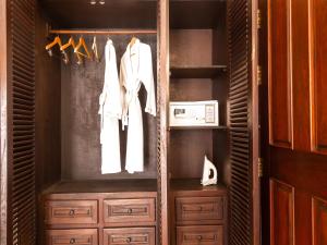 a closet with wooden cabinets and white clothes on hangers at Chateau d'Angkor La Residence in Siem Reap