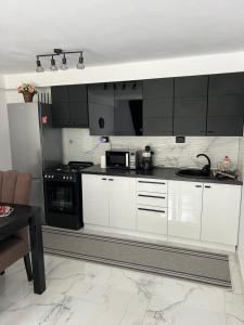 a kitchen with white cabinets and black appliances at Cabana Duda in Subcetate
