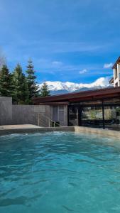 a swimming pool in front of a house with mountains at Apartmanica Double room apartment with balcony, St Ivan Rilski 4 star SPA Resort, Bansko in Bansko