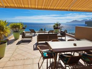 a patio with tables and chairs and a view of the ocean at Residence Veles Plage in Cannes