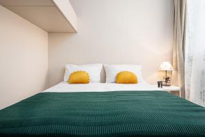 una camera da letto con un letto verde e bianco con cuscini gialli di Classbnb - Two apartments 500m from the skilifts a Breuil-Cervinia