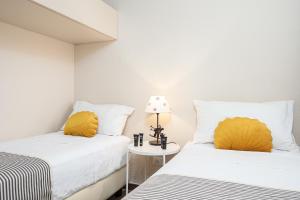 two beds with yellow pillows in a room at Classbnb - Two apartments 500m from the skilifts in Breuil-Cervinia