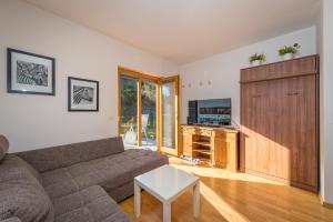 ein Wohnzimmer mit einem Sofa und einem TV in der Unterkunft Apartments Plan Kranjska Gora in Kranjska Gora