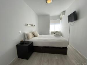 a white bedroom with a bed and a television at Apartamento Cuzco in Madrid