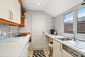 cocina con armarios blancos, fregadero y ventana en Comfortable 2 bedroom property, Maidstone en Maidstone