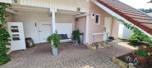 une terrasse couverte d'une maison avec un banc et des plantes dans l'établissement Villa Clee Ferienwohnungen, à Cleebronn