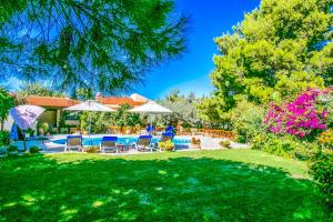 een tuin met een zwembad, stoelen en bomen bij Villa Agapi Episcopi in Episkopí