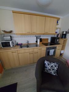 a kitchen with wooden cabinets and a sink and a couch at Ferienwohnung "Lützowhof" in Lübeck