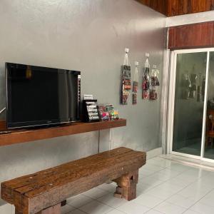 a television sitting on a wall with a wooden bench at PD Hostel in Ban Don Muang