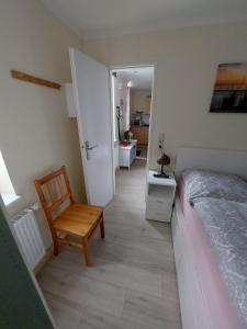 ein Schlafzimmer mit einem Bett und einem Stuhl neben einer Tür in der Unterkunft Ferienwohnung "Lützowhof" in Lübeck