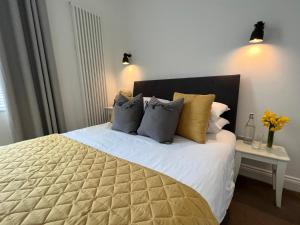 a bedroom with a large bed with yellow and gray pillows at Bouverie Bolthole in Folkestone