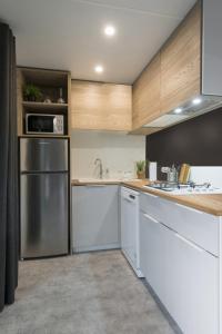 a kitchen with white cabinets and a stainless steel refrigerator at Sole Family Camping Village in Marina Romea