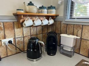 a kitchen counter with cups and appliances on the wall at Foundry Cottages in Rutherglen
