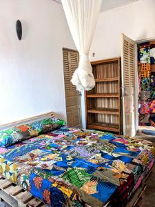 a bedroom with a large bed with a colorful quilt at Chambres d'hôtes - Chez Papa Sêdjro in Porto-Novo