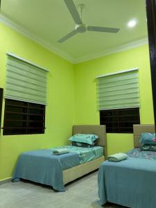 two beds in a room with yellow walls and windows at IJW HOMESTAY in Kuala Terengganu